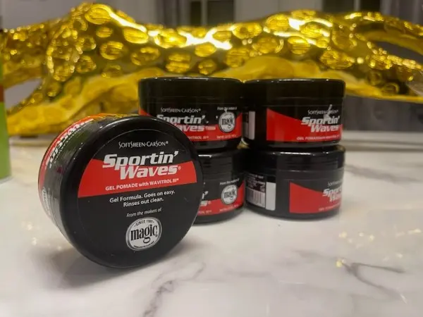 Pomades en gel Sportin' Waves avec Wavitrol de SoftSheen-Carson, plusieurs unités empilées et une au premier plan, montrant l'emballage noir avec des détails rouges et le logo de la marque.